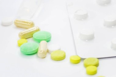 Pembe arka planda vitamin hapları ve beyaz çiçekli tıbbi konsept. Düz yatış, üst görünüm.