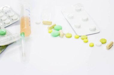 Pembe arka planda vitamin hapları ve beyaz çiçekli tıbbi konsept. Düz yatış, üst görünüm.