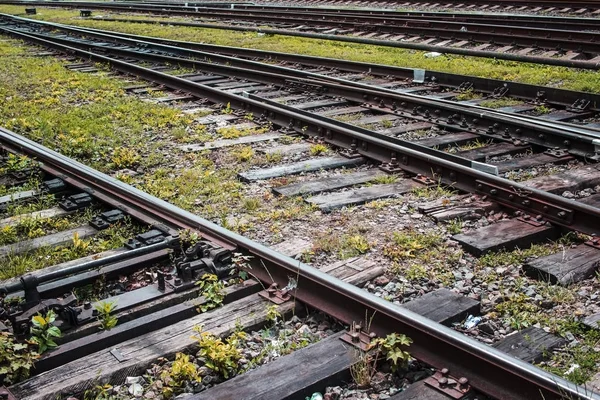 Close view of old railroad tracks with worn ties and gravel ballast in the summertime.