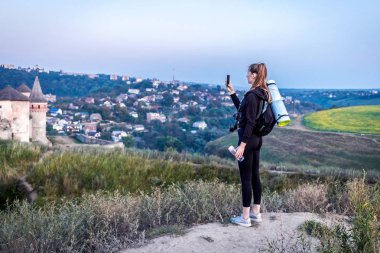 Seksi turist kız kamera ile. Tepe üzerinde bir güzel turist kız şafak bir kamera ile karşılamaktadır. Şehrin yukarısındaki bir yükseklik bir kıza doğa güzelliğe bakar.