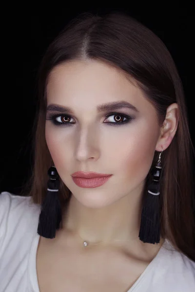 Beautiful young white girl close-up in a black jacket on a gray background in the studio. Makeup - blue smokeys, shades of metallic, lipstick bright glossy shine. Hairstyle - smoothly combed hair.