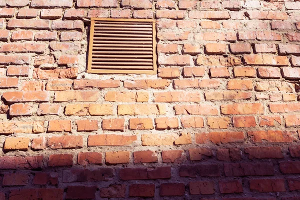 Uma pequena janela com uma treliça em uma parede de tijolo velho — Fotografia de Stock