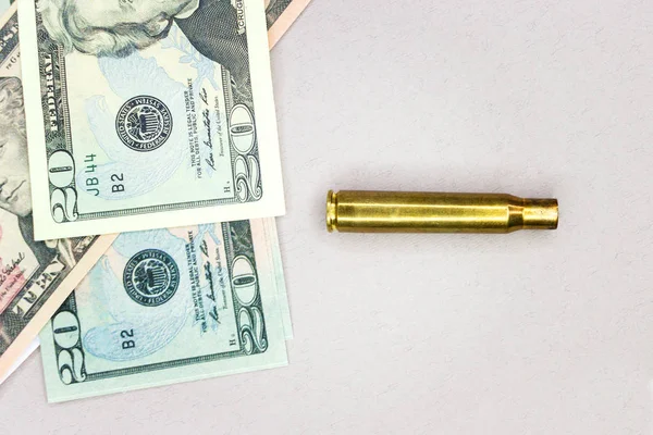 アメリカの100ドル紙幣の背景に9ミリメートルの貝殻。戦争と紛争でお金を稼ぐという概念. — ストック写真