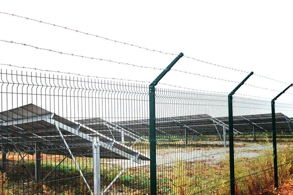 Solarmodul oder Photovoltaikpark hinter Metallkettenzaun auf der grünen Wiese mit dramatisch bewölktem Himmel in Norddeutschland lizenzfreie Stockbilder