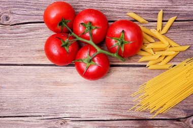Spagetti, kiraz domatesleri ve tahta bir masada maydanoz..