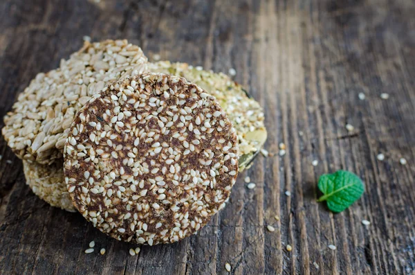 Dessert cereal snacks. Fitness dietary food. Kozinaki with dates, sesame, peanuts, sunflower and pumpkin seeds on old rustic wooden board, mint leaf. Vegetarian healthy nutrition concept.