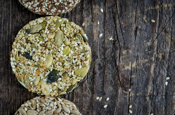 Dessert cereal snacks. Fitness dietary food. Raw diet kozinaki with sesame, peanuts, sunflower and pumpkin seeds on old rustic wooden board. Vegan healthy nutrition concept. Top view. Copy space.