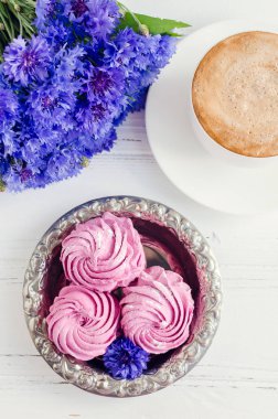 Pembe zephyr marshmallow cappuccino kahve ve Beyaz ahşap masa üzerinde mavi Peygamber buket ile. Üstten Görünüm.