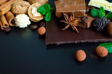 Farklı tür bir çikolata: karanlık, süt, şeker, fındık, tarçın ve anason yeşil nane ile gözenekli çubuklarıyla siyah arka plan üzerine bırakır. Seçici odak, yakın. Kopya alanı.