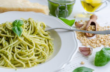 Beyaz ahşap masa üzerinde ev yapımı pesto soslu spagetti. Pesto alla Cenevizli ile makarna. İtalyan mutfağı kavramı.