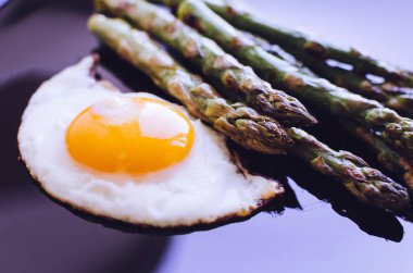 Sahanda yumurta ve taze kavrulmuş kuşkonmaz siyah plaka. Sağlıklı öğle yemeği kavramı. Yemek lezzetli, besleyici.