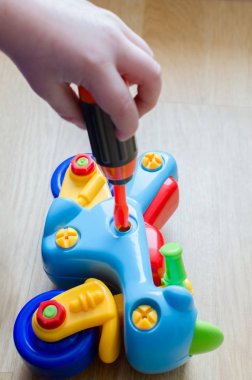 Çocuk bir motosiklet ile oynuyor. Bebek parmaklar oyuncak bir tornavida yardımı ile toplamak. Renkli Ayrıntılar çocuk dikkat çekmek. Oyun kapalı yerde gerçekleşir.