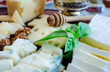 Peynir tabağı: Parmesan, kaşar peyniri, gouda, gorgonzola, brie ve diğer ceviz ve beyaz arka plan üzerinde ahşap tahta üzerinde tatlım. Lezzetli meze peynir farklı tipteki.