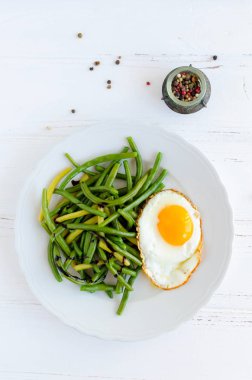 Pişmiş fasulye sosu Balzamico glassa ve ahşap arka plan üzerinde beyaz tabak içinde kızarmış yumurta ile. Sağlıklı vejetaryen gıda kavramı. Üstten görünüm.