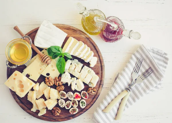 Peynir tabağı: Parmesan, kaşar peyniri, gouda, gorgonzola, brie ve diğer ceviz, zeytinyağı, sirke ve bal beyaz arka plan üzerinde ahşap tahta üzerinde. Lezzetli meze peynir farklı tipteki. Üstten görünüm.