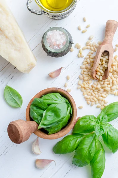 Pesto Cenevizli sos yukarıdan beyaz tahta masada için taze malzemeler. Harç, Parmesan peyniri, çam fıstığı, zeytin yağı, sarımsak ve tuz fesleğen yaprağı. Geleneksel İtalyan mutfağı. Üstten Görünüm.