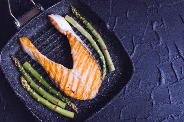 Izgara somon steak ve grill Pan siyah taş zemin üzerine hazırlanmış kuşkonmaz. Sağlıklı gıda kavramı. Üstten Görünüm. Kopya alanı.