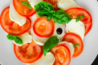 Tabak sağlıklı klasik lezzetli caprese salatası ile olgun domates ve mozzarella peyniri taze fesleğen ile karanlık beton arka plan üzerinde bırakır. İtalyan yemeği. Üstten Görünüm.