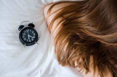 Genç kadın çalar saat sabahları yatakta yatmak. Uzun saçlı, alarmclock tanınmaz kızla. Öğrenci ya da öğrenci geç uyanmak korkuyor. Çalar saat anksiyete. Kavram fazla uyumak.