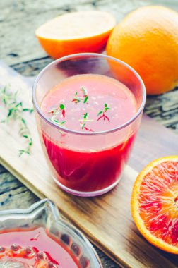 Eski ahşap desenli arka planda taze Sicilya kanı portakal suyu. Kekikle taze sıkılmış meyve suyu..