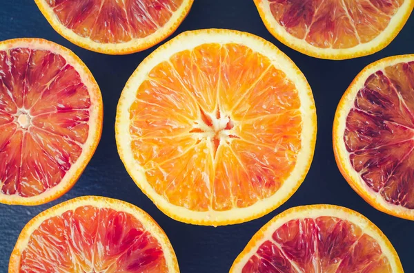 Sliced blood oranges texture. Citrus background. Cut ripe juicy Sicilian Blood oranges fruits on back background. Top view.