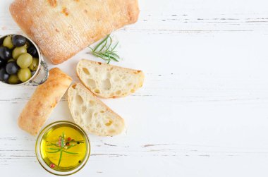 Geleneksel İtalyan ekmeği ciabatta biberiye, zeytinyağı ve zeytin beyaz rustik ahşap tablo taze pişmiş somun. İtalyan gıda kavramı. Üstten görünüm. Kopya alanı.