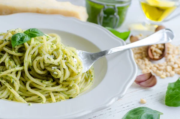 Beyaz ahşap masa üzerinde ev yapımı pesto soslu spagetti. Pesto alla Cenevizli ile makarna. İtalyan mutfağı kavramı.