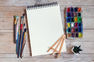 Yaratıcı sanatçı çalışma alanı düz yatıyordu, mockup. Üstten görünüm tablo boş sketchbook, boya fırçaları ve boya paletleri ile. Sanat Atölyesi, resim, çizim, el sanatları, yaratıcılık kavramı. Kopya alanı.