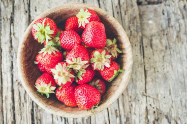 Taze hasat çilek. Ahşap kase etli sulu taze Olgun kırmızı çilek üzerinde eski bir ahşap dokulu masa üstü dolu. Üstten görünüm.