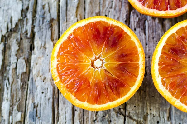 Sliced blood oranges texture. Citrus background. Cut ripe juicy Sicilian Blood oranges fruits on old wooden background. Top view. Copy space.