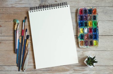 Yaratıcı sanatçı çalışma alanı düz yatıyordu, mockup. Üstten görünüm tablo boş sketchbook, boya fırçaları ve boya paletleri ile. Sanat Atölyesi, resim, çizim, el sanatları, yaratıcılık kavramı. Kopya alanı.