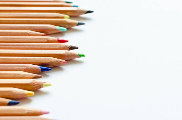 Wooden color pencils on empty white paper. Minimalist template with copy space close up macro.
