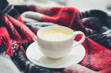 Bir bardak limonlu çay ve pencere pervazında sıcak yün battaniye. Yağmurlu günler için sıcak içecek. Hygge konsepti, sonbahar havası. Evde sıcak bir kış sabahı. Sıcak ve rahat bir sonbahar tatili. Soğuk havada dinleniyor..