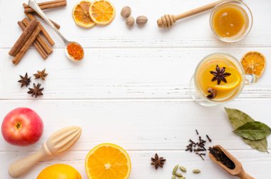 Sıcak beyaz mulled şarap cam portakal, tarçın ve anasonu baharat ve malzemelerin üzerine beyaz tahta arka plan ile. Baharatlı sıcak içecek. Mevsimlik sıcak içecek. Uzay kopyalayın. Üstten görünüm.