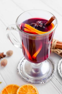 Sıcak kırmızı şarap veya gluhwein cam portakal, tarçın ve anason Beyaz ahşap zemin üzerinde mulled. Baharatlı sıcak içecek. Mevsimlik sıcak içecek.