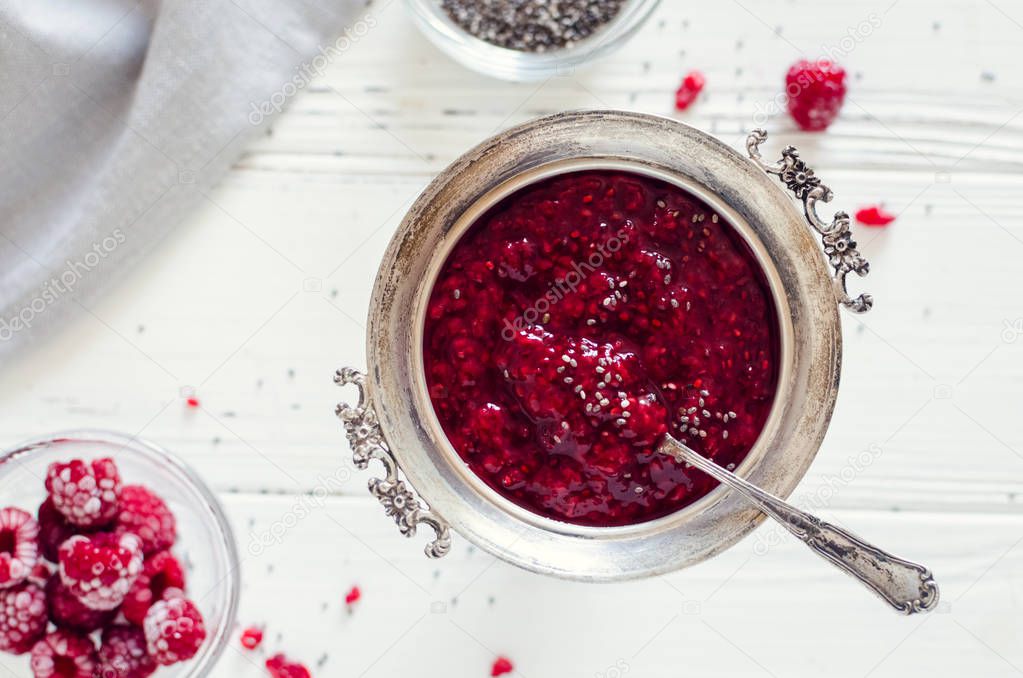 Homemade raspberry jam with chia seeds on white background. Healthy idea for breakfast toasts. Superfoods and healthy food concept. Top view.
