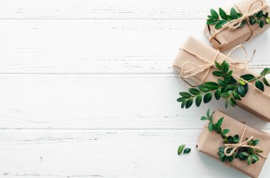 Modern Noel hediyeleri beyaz ahşap arka planda doğal dekor ile paketlenmiş. El sanatları kağıdında sicim ve yeşil dallarla kutular. Mevsimlik tebrik kartı. Üst Manzara. Düz yatıyordu. Boşluğu kopyala.