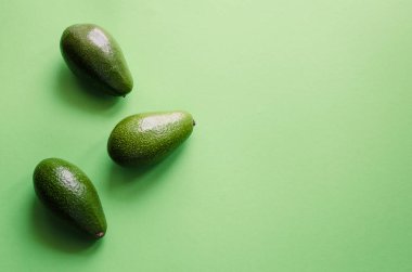 Organik avokado rengi yeşil zemin üzerine. Pop sanat tasarım, yaratıcı yaz gıda kavramı. Yeşil avocadoes desen en az daire yatıyordu tarzı. Üstten görünüm. Kopya alanı.