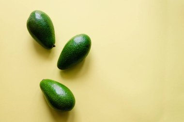 Organik avokado rengi sarı zemin üzerine. Pop sanat tasarım, yaratıcı yaz gıda kavramı. Yeşil avocadoes desen en az daire yatıyordu tarzı. Üstten görünüm. Kopya alanı.