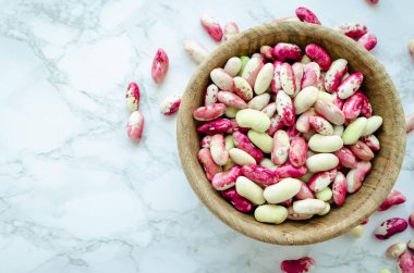 Taze organik mor tahıl-beens mermer masada ahşap kase. Kuru fasulye vegan protein kaynağı. Dengeli beslenme, yemek, vejetaryen ve temiz kavramı yeme. Sağlıklı gıda. Üstten görünüm. Kopya alanı.