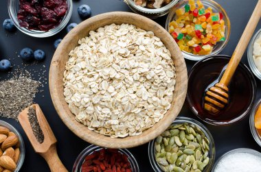 Ev yapımı granola için malzemeler: yulaf, chia ve kabak tohumu, kızılcık ve badem, Hindistan cevizi ve agav nektar, goji meyveleri ve taze yaban mersini. Superfood. Üstten görünüm. Düz yatıyordu.