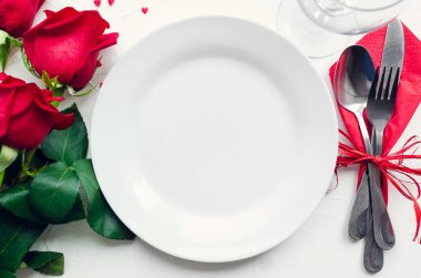 Sevgililer günü romantik tabble ayarıyla kırmızı gül, tabak, çatal bıçak takımı beyaz arka plan üzerinde. Boş levha. Mockup tasarım düzeni metniniz için. Aşk Sevgililer kavramı. Uzay kopyalayın. Üstten görünüm. Düz yatıyordu.