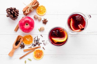 İki bardak sıcak kırmızı şarap veya gluhwein ile portakal, tarçın ve anason Beyaz ahşap zemin üzerinde mulled. Baharatlı sıcak içecek. Mevsimlik sıcak içecek. Üstten görünüm. Kopya alanı.