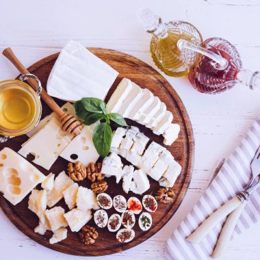 Peynir tabağı: Parmesan, kaşar peyniri, gouda, gorgonzola, brie ve diğer ceviz, zeytinyağı, sirke ve bal beyaz arka plan üzerinde ahşap tahta üzerinde. Lezzetli meze peynir farklı tipteki. Üstten görünüm.