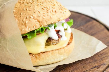 Burger sığır eti, domates, peynir, kırmızı soğan ve marul ahşap tahta üzerinde. Lezzetli taze ev yapımı hamburger Close-up. Fast food kavramı. Seçici odak.
