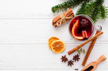 Sıcak kırmızı şarap cam portakal, tarçın ve anasonu malzemelerle Beyaz ahşap zemin üzerinde mulled. Baharatlı sıcak içecek. Mevsimlik Noel içki mulled. Uzay kopyalayın. Üstten görünüm.