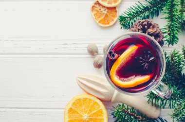 Sıcak kırmızı şarap cam portakal, tarçın ve anasonu malzemelerle Beyaz ahşap zemin üzerinde mulled. Baharatlı sıcak içecek. Mevsimlik Noel içki mulled. Uzay kopyalayın. Üstten görünüm.