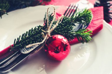 Aile Noel kutlaması sofra konsepti. Köknar ağacı dalları, mumlar ve çam kozalaklarının doğal süslemeleriyle bayram yemeği için güzel bir yer..