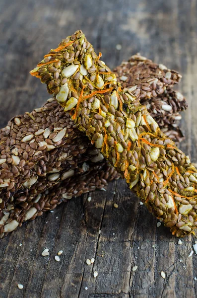 Healthy raw dessert snack. Fitness dietary food. Homemade breadsticks with carrot, flax, sunflower, pumpkin seeds on the rustic wooden board. Vegetarian nutrition concept. Copy space.