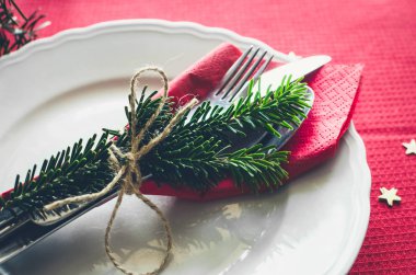 Aile Noel kutlaması sofra konsepti. Köknar ağacı dalları, mumlar ve çam kozalaklarının doğal süslemeleriyle bayram yemeği için güzel bir yer..